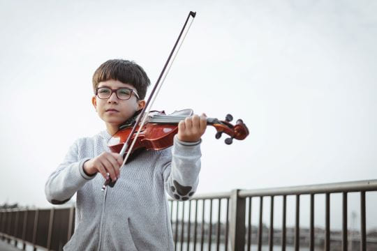 petit garçon qui joue du violon à l'extérieur pour un babysitting à Paris 17