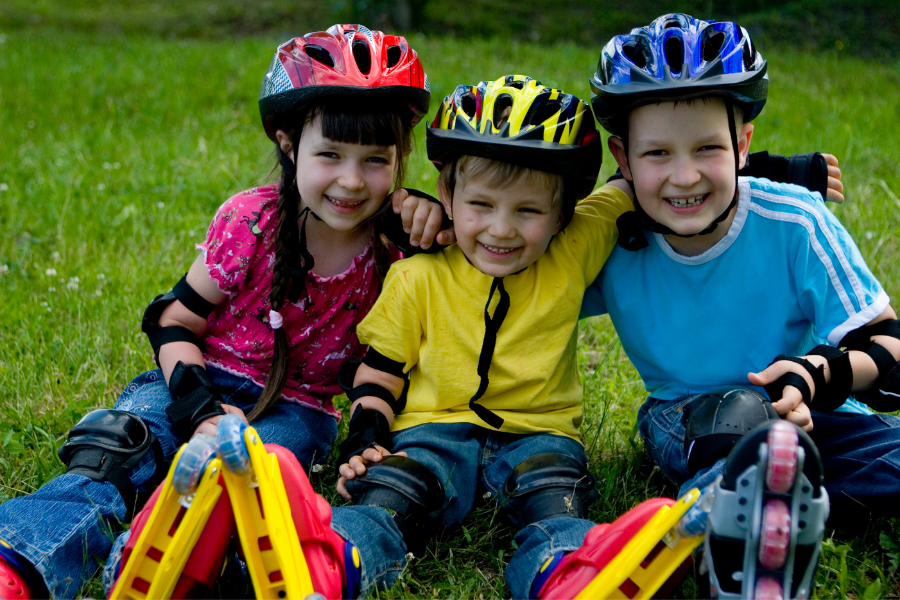 trois enfants assis par terre, ils portent des rouler et un casque. Une image illustrant les bienfaits du sport