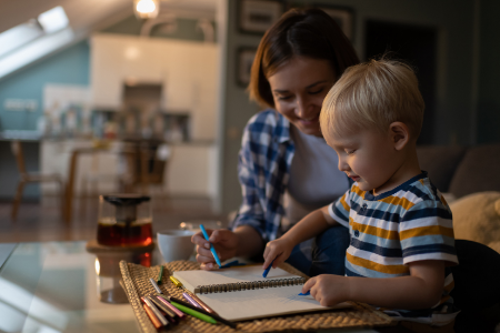 Une babysitter et un enfant qui dessine dans un cahier lors d'un babysitting