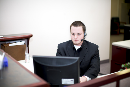 Homme installé à un bureau devant son ordinateur, avec un micro pendant son job étudiant