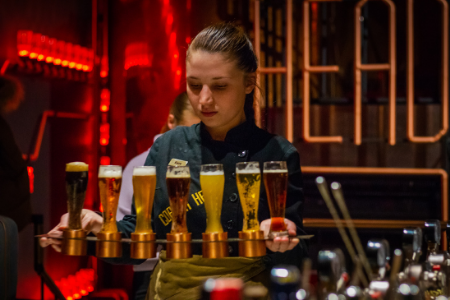 jeune fille tenant un plateau rempli de verres comme serveuse pour son job étudiant