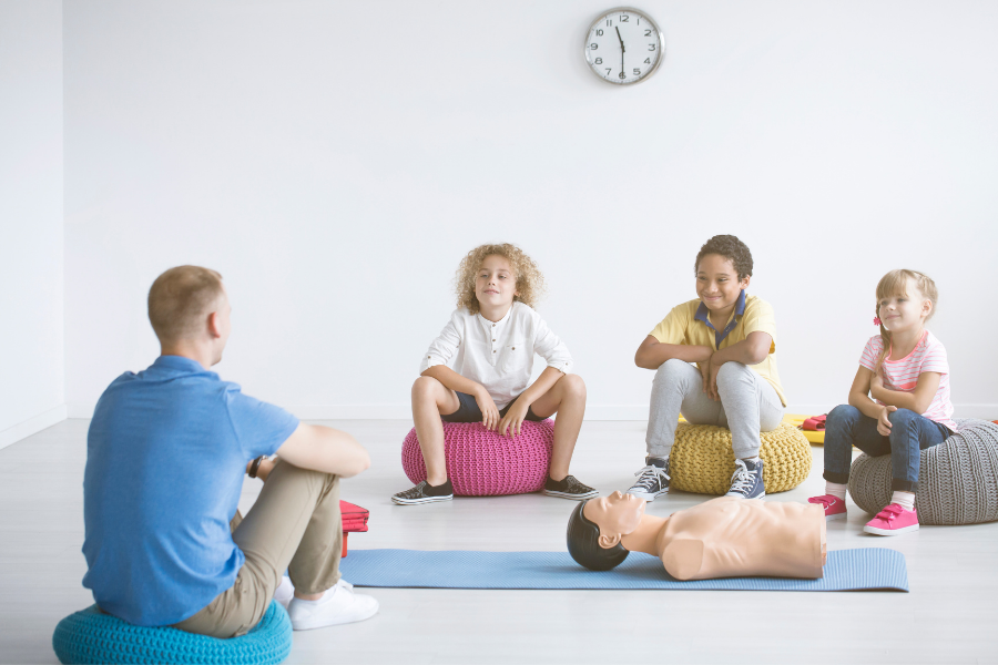trois enfants assistant à un cours sur les gestes de premiers secours
