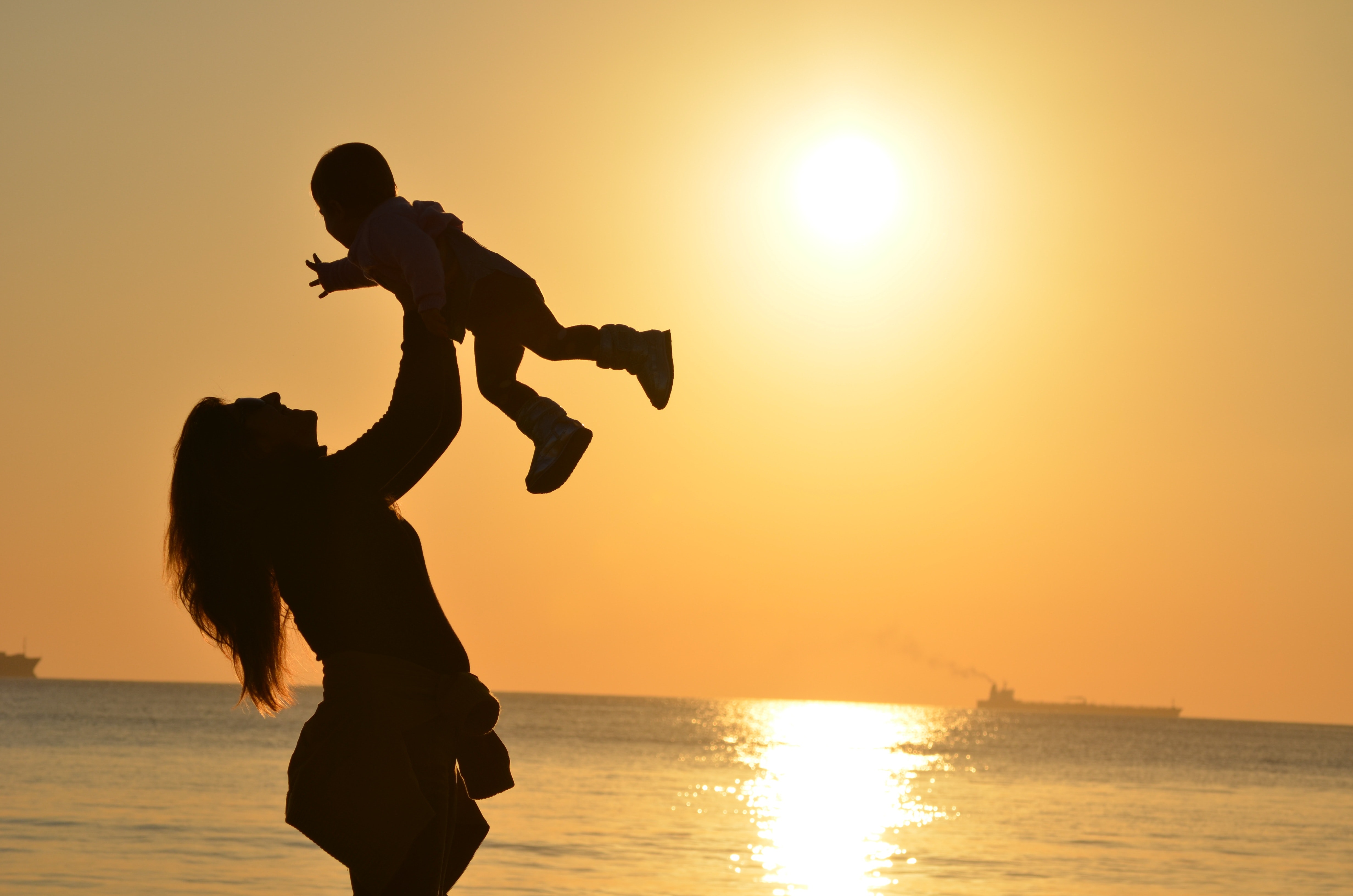 Une maman joue avec son enfant devant le coucher du soleil