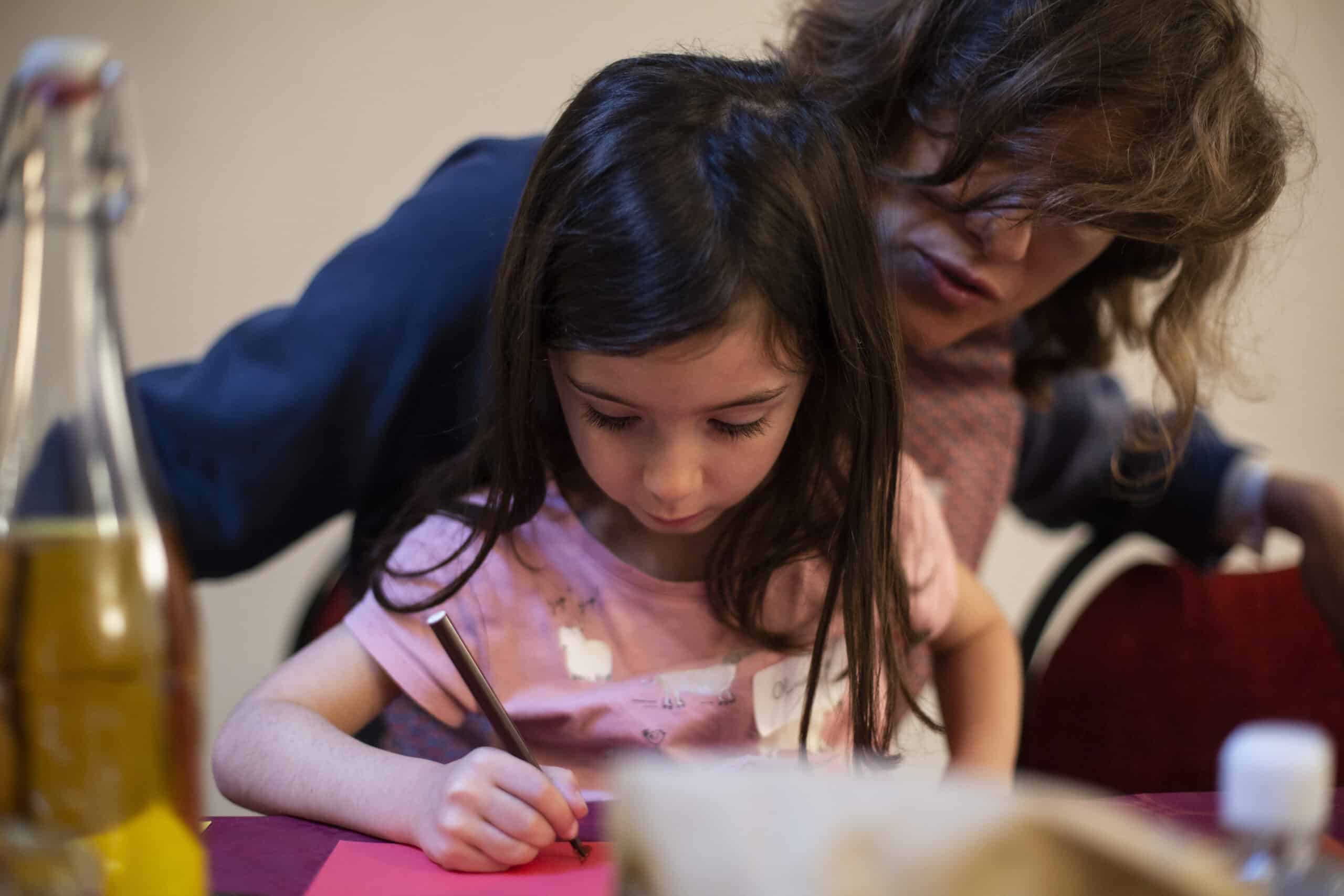 étudiante accompagnant une enfant qui écrit, job étudiant aide aux devoirs